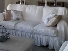 a living room with white couches and pillows on the back of it's loveseat