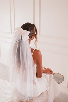 a bride sitting on the floor with her hair in a bun and veil over her head