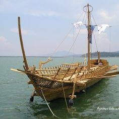 an old wooden boat is in the middle of the water with two masts on it