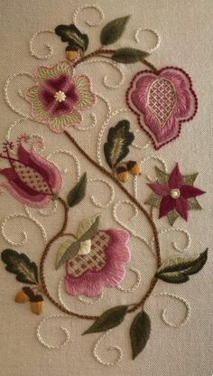 a close up of a piece of embroidered fabric with flowers and leaves on the side