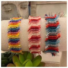 three different colored bracelets on top of each other next to a succulent plant