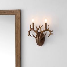 a deer's head is mounted on the wall next to a mirror and two candles