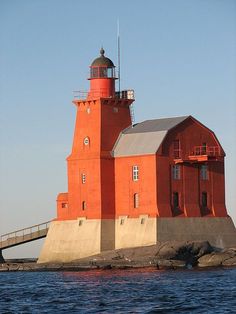 an orange light house sitting on top of a body of water