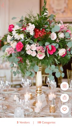 a vase filled with pink and red flowers on top of a table covered in white plates