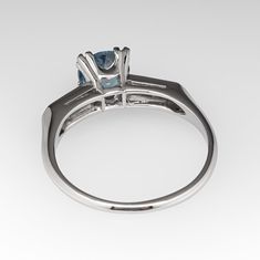 This stunning light icy teal sapphire engagement ring is centered with a round brilliant cut no heat Montana sapphire that we sourced and set in a vintage platinum diamond mounting. The shoulders are each bead set with three (3) round brilliant cut diamonds. The ring measures 7.3mm at the top, rises 7.3mm above the finger, tapering to 1.5mm wide and 1.2mm thick at the base of the shank. The ring is currently a size 9 and we offer complimentary sizing to fit. Classic Sapphire Solitaire Topaz Ring, Classic Birthstone Ring With Round Cut Blue Topaz, Classic Round Cut Blue Topaz Birthstone Ring, Classic Blue Topaz Birthstone Ring, Round Cut, Classic Blue Topaz Birthstone Ring, Classic Asscher-cut Sapphire Ring With Diamond Accents, Classic Sapphire Topaz Ring With Round Cut, Classic Sapphire Topaz Ring With Center Stone, Classic Asscher Cut Sapphire Ring With Diamond Accents