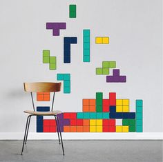 a chair sitting in front of a wall with colorful blocks on it's side