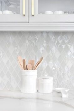 a kitchen counter with white cabinets and utensils in the holder on top of it