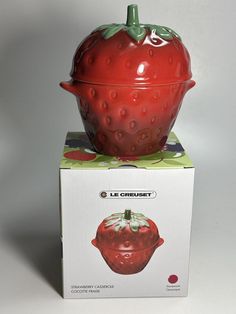 a large red strawberry sitting on top of a box next to it's lid