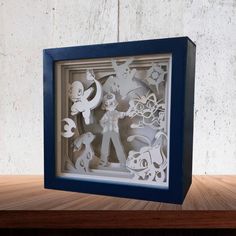 an origami cut out of paper in a blue frame on a wooden table