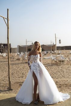 a woman in a wedding dress standing on the beach