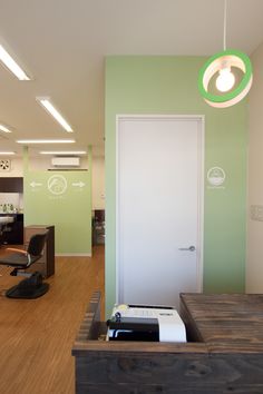 an office with green walls and wood flooring on the ground, along with a door that leads to another room