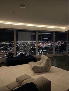 a living room filled with furniture and large windows overlooking the city at night in the distance