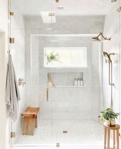 a bathroom with a walk in shower next to a wooden bench and potted plant