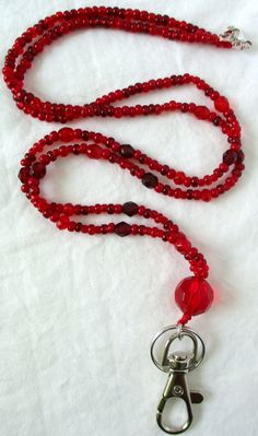 Red Beaded Lanyard This Red Beaded Lanyard can be used as a badge holder, an I.D. holder, keychain necklace, watch holder - it's a multi-use accessory for home or office! 34" in length, long enough to put on or remove overhead. It also has an easy-to-use metal lobster clasp for your convenience. It's made with red glass beads and strung on strong C-Lon beading cord. Snap-on badge holder, clip, and keyring are included to keep your badges or keys ready when you need them. This Red Beaded Lanyard Red Lanyards With Key Leash, Adjustable Red Lanyard With Key Leash, Adjustable Red Lanyard As Gift, Red Lanyard With Key Leash As Gift, Red Lanyards With Key Leash For Gifts, Keychain Necklace, Beading Cord, Beaded Lanyard, Watch Holder