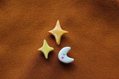 two small plastic stars and a crescent on an orange cloth, one with a yellow star