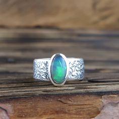 An Ethiopian Welo Opal gemstone set in a .999 fine silver ring. US Ring Size 6 1/4 Opal weight: 1.35ct Ring weighs 12.5g including stone. Opal including setting measures 11mm by 7mm Ring band width: 8mm All metal parts are handmade using .999 fine silver All cabochons are cut and polished by myself. Handmade by Mike Summers. Looking after your opal... Ethiopian opals are hydrophane opals, which mean they absorb water. They can temporarily lose color if they get wet, but the color will start to return. It's usually best to avoid wearing if swimming, or where it will be submersed in water. Your opal can be washed in water and then dried with a soft cloth. Do not use chemical cleaners or ultrasonic cleaners and keep them free from oils, perfumes and lotions. We are husband and wife Mike and A Oval Sterling Silver Opal Ring With Stone Setting, Artisan Sterling Silver Oval Opal Ring, Artisan Oval Opal Ring In Sterling Silver, Opal Silver Ring, Metal Jewellery, Welo Opal, Ring Band, Opal Gemstone, Fine Silver