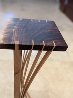 a wooden table with sticks sticking out of it's sides on a tile floor