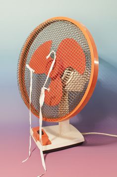 an orange fan sitting on top of a white stand