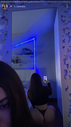 a woman taking a selfie in front of a mirror with blue lights on it