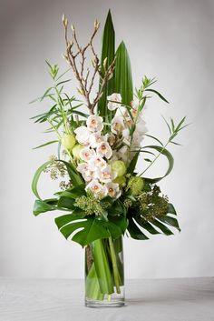 a vase filled with white flowers and greenery