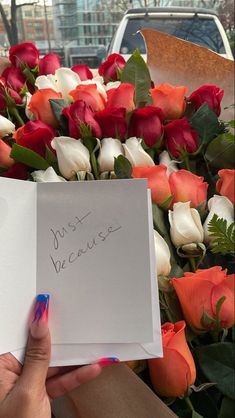 a person holding a piece of paper with writing on it in front of a bunch of roses