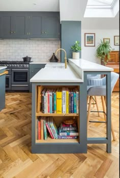 a kitchen with an island and bookshelf in the center, surrounded by wooden flooring