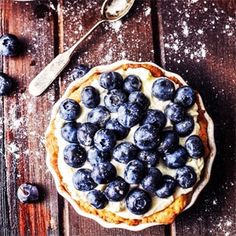 a pie topped with blueberries on top of a wooden table