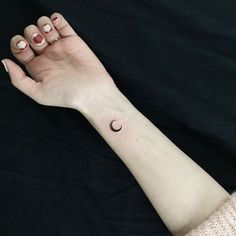 a woman's arm with a small crescent tattoo on it and a black background