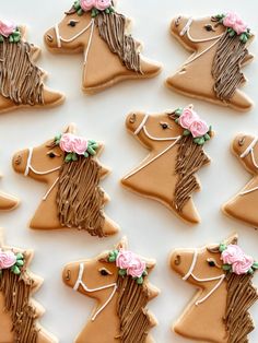 decorated cookies in the shape of horses with pink flowers on their heads are arranged neatly