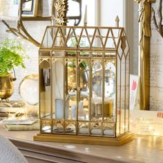 a golden birdcage is sitting on a table next to a mirror and other items