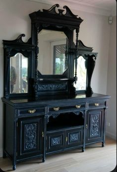 an ornate black dresser and mirror in a room