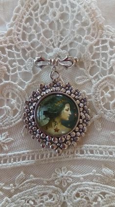 "With beautiful watery color and wonderful clarity, encased in an antiqued silver tone setting, our 'Aquarius, The Water Bearer' brooch measures 2.5 inches in length. The artwork is set under a high quality glass dome.  Every item in our shop is handmade, and created with loving care.   Please note: The glare on the cameo occurs from the photo and is not a blemish on the piece. Our cameos are resistant but not waterproof and should not be submerged in water or worn when swimming or bathing. For your timeless style! Your treasures come tucked into a lovely organza bag.  If your order is being sent directly to a gift recipient, we are delighted to take part in your thoughtfulness, and are happy to include a card with your personal message.  Simply include your message in the \"message to sel Handmade Artistic Silver Brooch, Silver Art Nouveau Brooches As Gift, Silver Art Nouveau Brooches For Gifts, Silver Medallion Brooches For Collectors, Silver Medallion Brooches As A Gift, Antique Silver Vintage Brooches As Gift, Constellation Aquarius, The Water Bearer, Aquarius Gifts