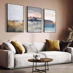 a living room with three paintings on the wall and a coffee table in front of it