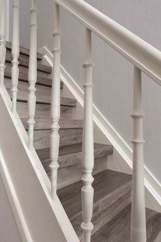 the stairs are painted white and have wood balustings on them, along with gray walls