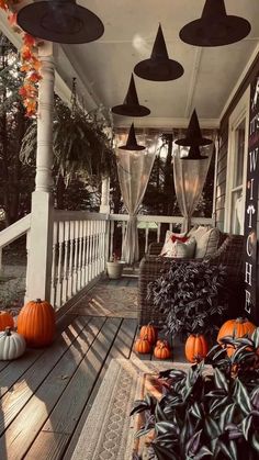 an outdoor porch decorated for halloween with pumpkins and witch hats hanging from the ceiling