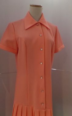 This salmon pink dress is vintage hipster with its dropped waist and accordian pleats. It has a 1920s style with the silhouette. The label is A Yardley Fashion. It is machine washable. Twiggy wore one of Gibbs dresses to her premiere which heightened the popularity of his label. He became perhaps most famous for his extraordinary knitwear designs, undeniably inspired by his Scottish origins. Initially hand machined by Mildred Boulton, who worked from Gibb's designs and Kaffe Fassett's swatches, Pink Fitted Dress With Accordion Pleats, Fitted Pink Dress With Accordion Pleats, Spring Retro Pleated Vintage Dress, Retro Pink Dress With Buttons, Retro Pink Collared Dress, Vintage Pink Dress For Work, Vintage Pink Collared Dress, Pink Vintage Collared Dress, Retro Pink Dress For Work