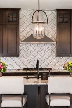 a kitchen island with two chairs and a light hanging over the stove top in front of it