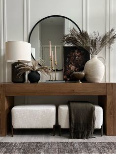 a wooden table topped with vases filled with plants and flowers next to a mirror