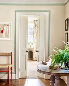 a room with a table, chair and pictures on the wall above it that has a door leading to another room