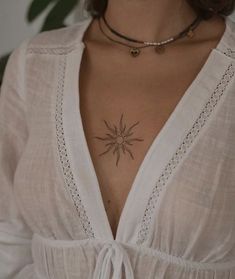 a woman wearing a white shirt with a black star tattoo on her chest and neck