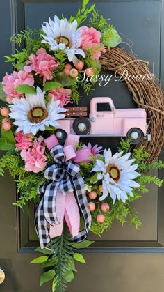 a wreath with flowers and a pink truck is hanging on the front door for someone to welcome