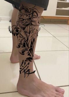 a woman's leg with tattoos on it and an image of a demon in the background