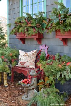 a red bench sitting in front of a house filled with potted plants