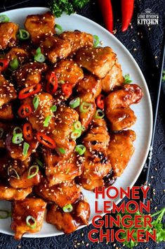 a white plate topped with chicken covered in sesame seeds and red peppers next to chopsticks