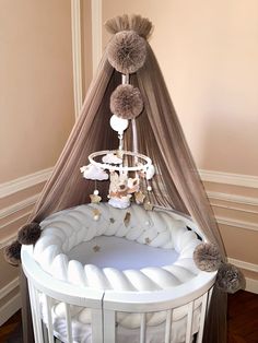 a baby crib that has some balls on top of it and two pom poms hanging from the ceiling