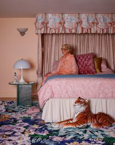 a woman sitting on top of a bed next to a tiger laying on the floor