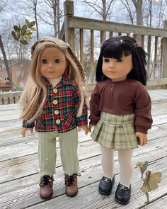 two dolls standing next to each other on a wooden deck