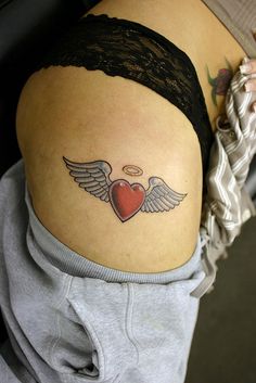 a woman's stomach with an angel heart tattoo on her lower back and wings