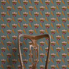 an old wooden chair sitting in front of a wallpaper with flowers on the back