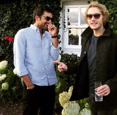 two men standing next to each other talking on cell phones